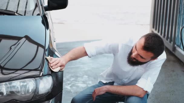 髭を生やした男が洗車場で布で車を洗う — ストック動画