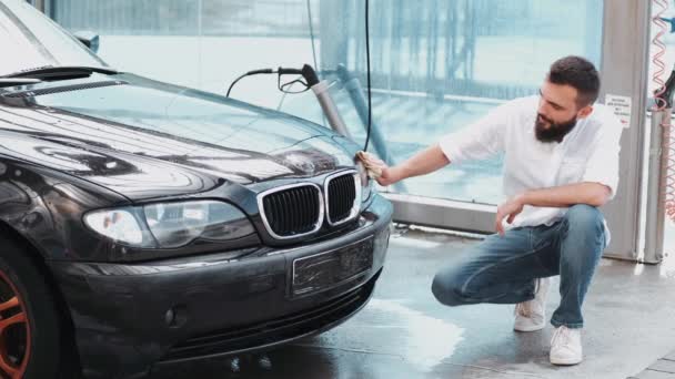 Baard man wassen van auto met doek bij car wash — Stockvideo