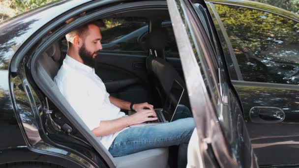Mann im Hemd sitzt mit Laptop auf Rücksitz — Stockvideo