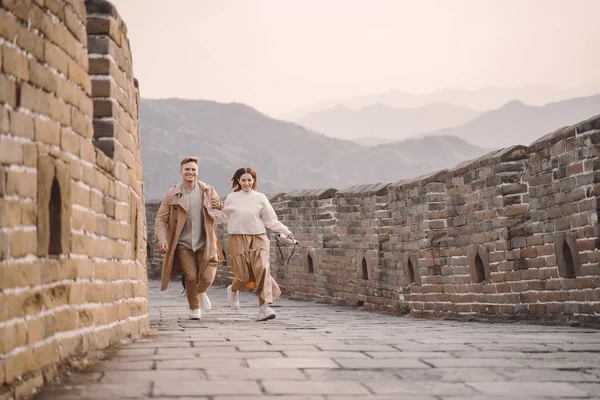Молодая пара, бегающая и вертящаяся у Великой Китайской стены — стоковое фото