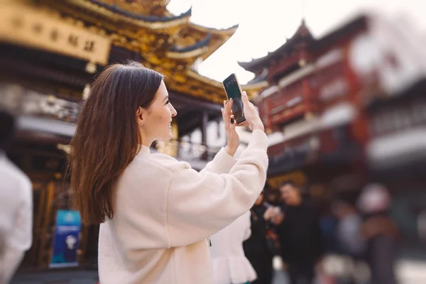 Brunetka dziewczyna robi zdjęcia na jej telefon z a pagoda w Yuyuan — Zdjęcie stockowe