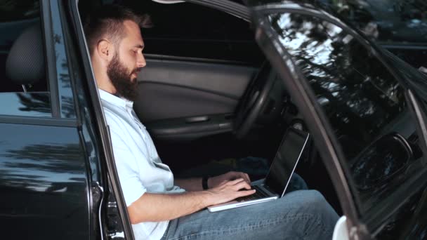 Homem sentado no banco da frente do carro preto com laptop — Vídeo de Stock
