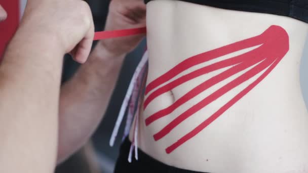 Persona con cinta de cinesiología roja en el estómago en clínica privada — Vídeos de Stock