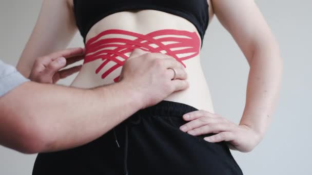 Therapeut het plaatsen van kinesiology tape op vrouwen schouder in kliniek — Stockvideo