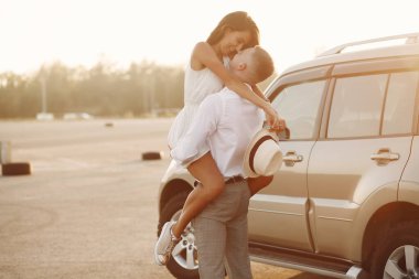 Güzel bir çift, bir yaz parkında bir arabanın yanında vakit geçirir.