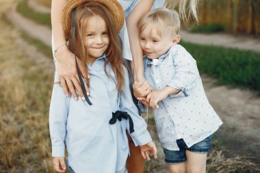 Anne ve çocuklar yaz tarlasında oynuyorlar.