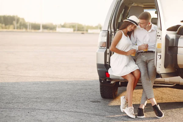 Beautiful couple spend time in a summer park near a car — 스톡 사진