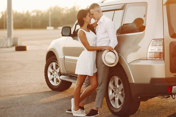 这对年轻漂亮的夫妇在汽车旁边的一个夏季公园里消磨时光 — 图库照片