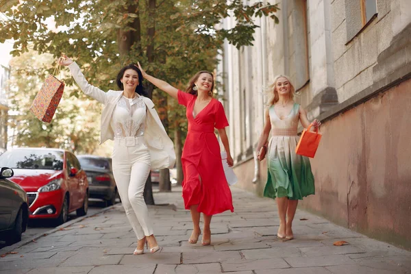 Három elegáns nő bevásárló táskákkal egy városban. — Stock Fotó