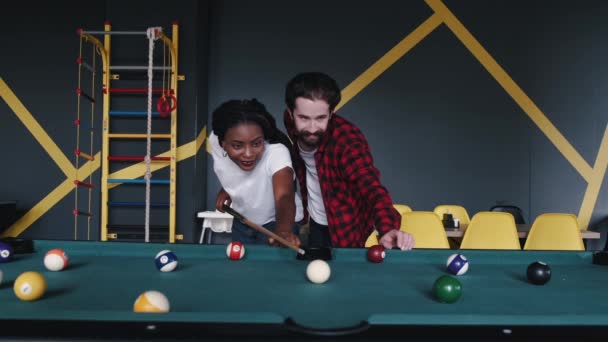 Бородатый мужчина и афроамериканка играют в бильярд — стоковое видео