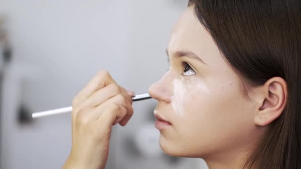 Primer plano de la cara femenina mientras se hace maquillaje en el salón de belleza — Vídeo de stock