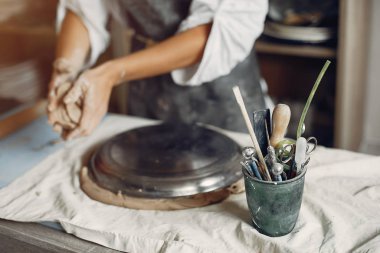 Genç bir kadın çömlekçide bulaşık yapıyor.