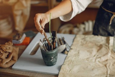 Genç bir kadın çömlekçide bulaşık yapıyor.