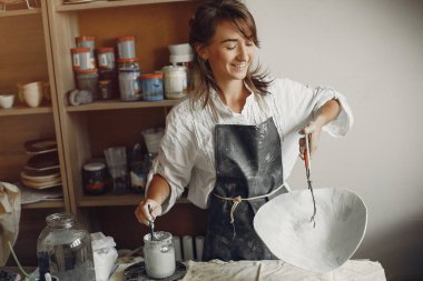 Genç bir kadın çömlekçide bulaşık yapıyor.