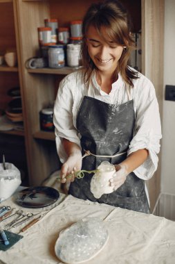 Genç bir kadın çömlekçide bulaşık yapıyor.