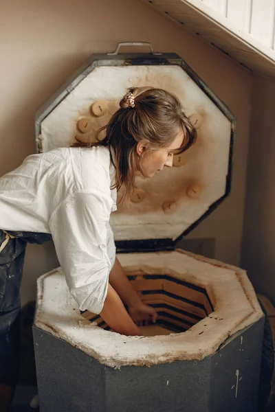 Een jonge vrouw maakt gerechten in een aardewerk — Stockfoto