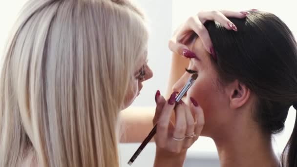 Крупный план визажиста, делающего макияж для клиента в салоне — стоковое видео