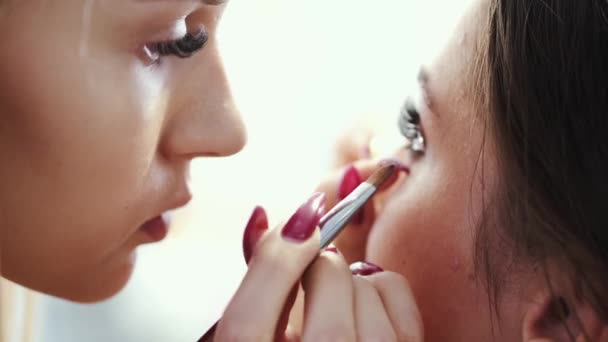 Крупный план визажиста, делающего макияж для клиента в салоне — стоковое видео