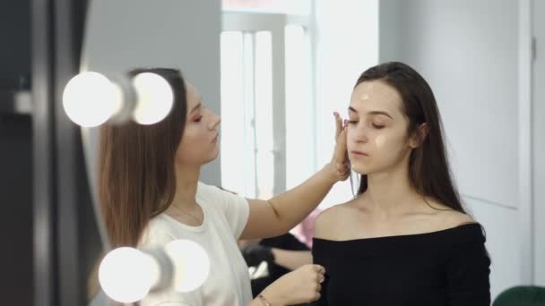 Artista de maquillaje haciendo tonelada de piel para el cliente en el salón — Vídeos de Stock