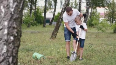 European father and son are starting to dig a hole in a park