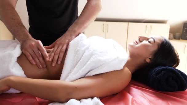 Терапевт делает массаж живота брюнетке — стоковое видео
