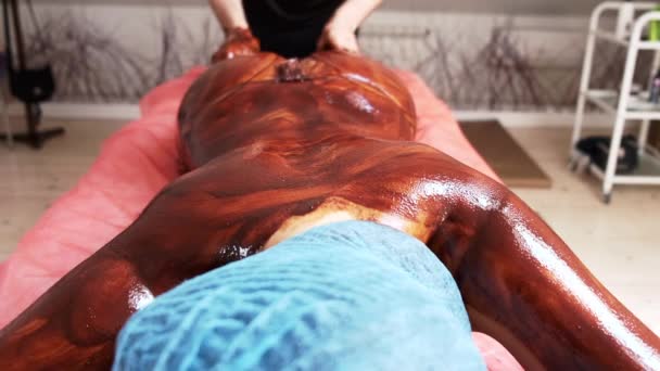 Masseur faisant masque au chocolat pour le corps des clients dans le spa — Video