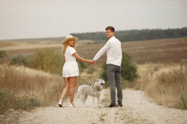 Sonbahar tarlasında bir çift köpekle oynuyor.
