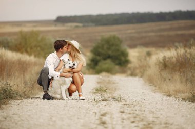 Sonbahar tarlasında bir çift köpekle oynuyor.