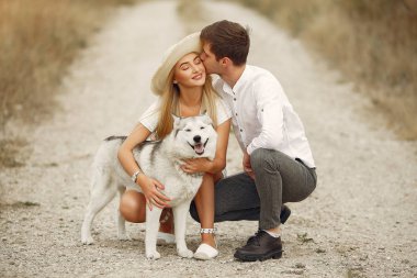 Sonbahar tarlasında bir çift köpekle oynuyor.