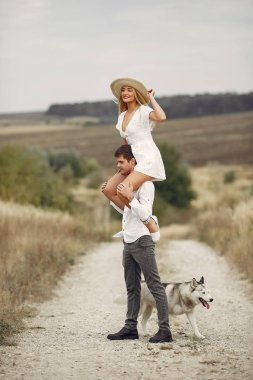 Sonbahar tarlasında bir çift köpekle oynuyor.