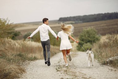Sonbahar tarlasında bir çift köpekle oynuyor.