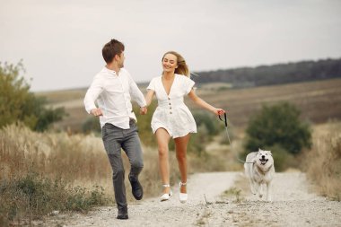 Sonbahar tarlasında bir çift köpekle oynuyor.