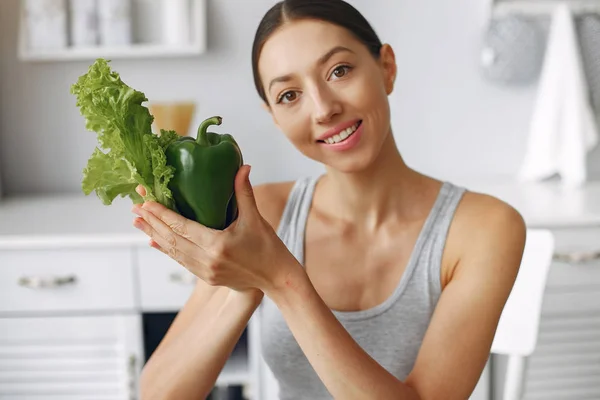 Schöne und sportliche Mädchen in einer Küche mit Gemüse — Stockfoto