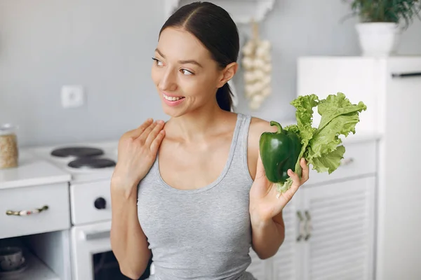 Menina bonita e desportiva em uma cozinha com um legumes — Fotografia de Stock