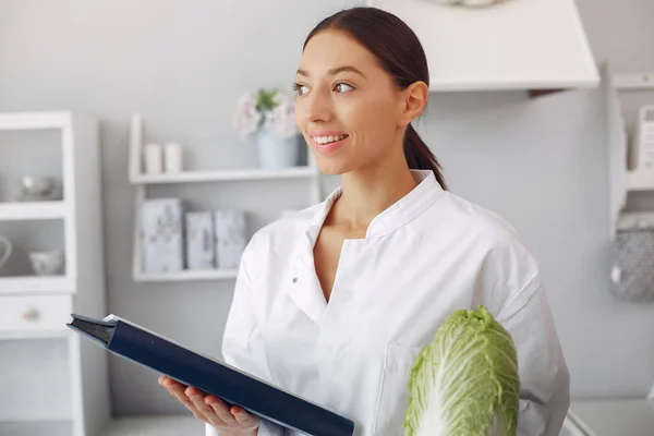 Schöne Ärztin in einer Küche mit Gemüse — Stockfoto