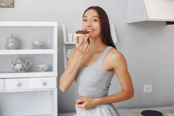 Menina bonita de pé em uma cozinha com donut — Fotografia de Stock