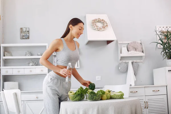 Menina bonita e desportiva em uma cozinha com um legumes — Fotografia de Stock