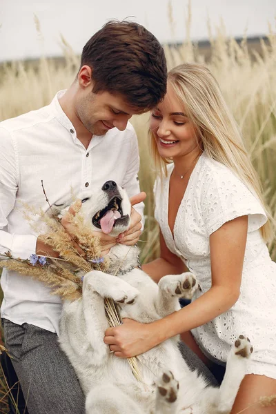 Coppia in un campo autunnale che gioca con un cane — Foto Stock