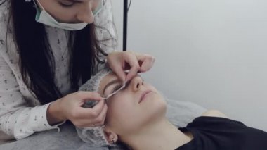 Kirpik yapıcı bir yüze göz bandı uyguluyor.
