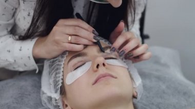 Kirpikçi gözüne kaldırma pedi yapıştırıyor.