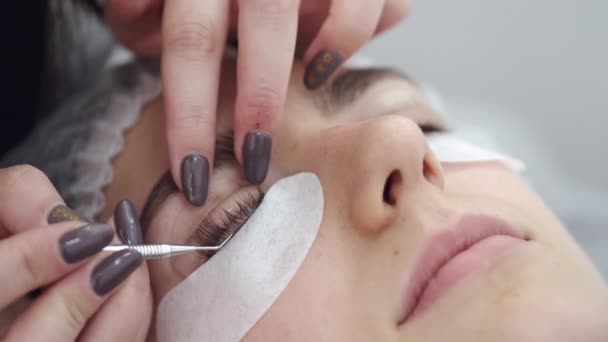 The lash technician is curling the eye lashes up with a tool — Stockvideo