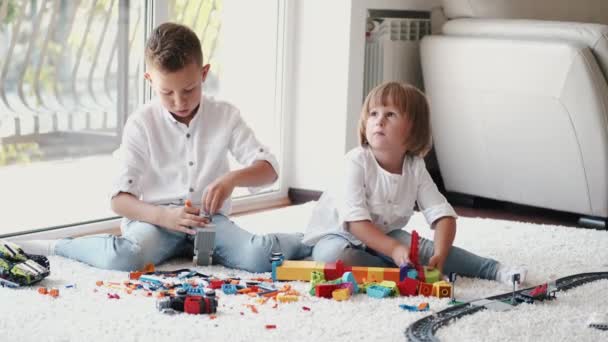 Kakak dan adik bermain dengan lego di lantai di rumah — Stok Video