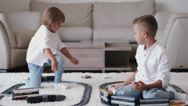 Dos niños jugando con el ferrocarril de juguete juntos en casa — Vídeo de stock