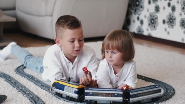 Портрет брата і сестри, що грає з іграшковою залізницею вдома — стокове відео