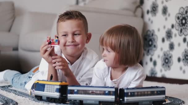 家でおもちゃの鉄道で遊んでいる兄と妹の肖像 — ストック動画
