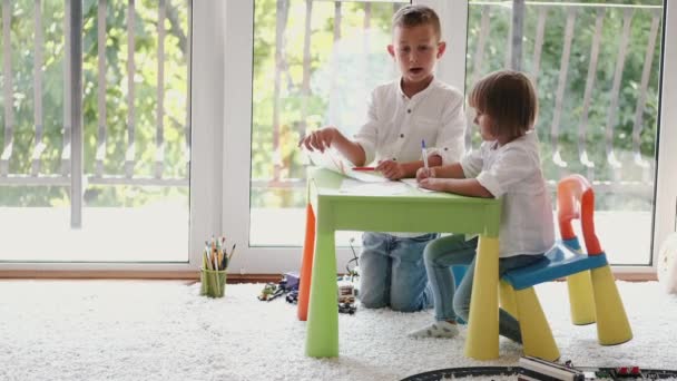 Due bambini che disegnano insieme a casa con matite colorate — Video Stock