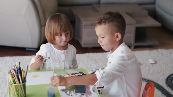 Retrato de dos niños sosteniendo pinceles y dibujo en casa — Vídeos de Stock