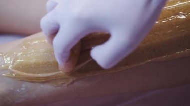 Kılların alınması için müşterilerin bacağına balmumu konması