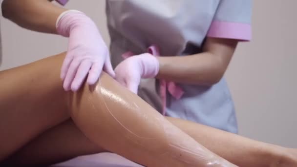 Косметолог делает депиляцию ног клиентов в салоне красоты — стоковое видео