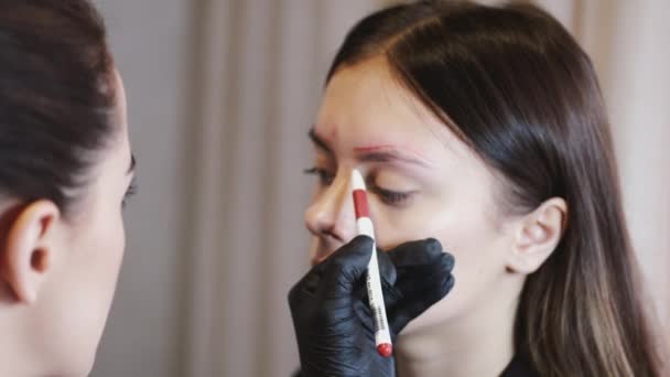 Der Brauenkünstler id beim Mapping der Brauen vor dem Microblading-Verfahren mit einem roten Stift — Stockvideo